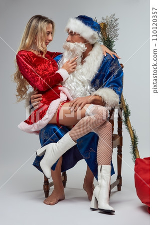 Playful Santa Claus in blue costume with his sexy assistant 110120357