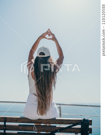 Woman summer travel sea. Happy tourist enjoy taking picture outdoors for memories. Woman traveler posing over sea bay surrounded by volcanic mountains, sharing travel adventure journey 110120588