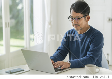 A man in his 50s working on a laptop 110123101