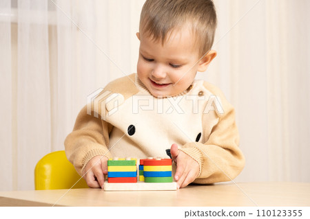 A two-year-old boy plays with wooden toys to develop logic and motor skills A two-year-old boy plays with wooden toys to develop logic and motor skills 110123355