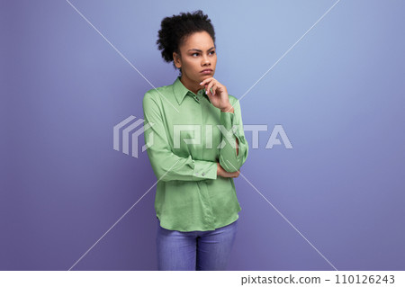 young smart latin woman dressed in a green shirt points towards the wall with copy space young smart latin woman dressed in a green shirt points towards the wall with copy space 110126243