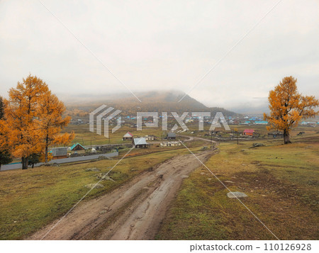 Autumn dirt road from a hill to a remote village. 110126928