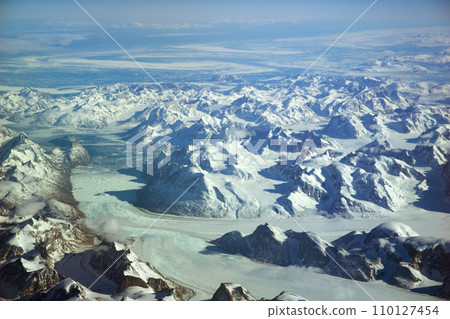 GREENLAND - 10 MAY 2018: View from the aircraft window of icy landscape with glaciers and snow-capped mountains of Greenland GREENLAND - 10 MAY 2018: View from the aircraft window of icy landscape with glaciers and snow-capped mountains of Greenland 110127454