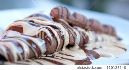 White plate with merengue cookies and chocolate decoration. Closeup of banana Pavlova White plate with merengue cookies and chocolate decoration. Closeup of banana Pavlova 110128348