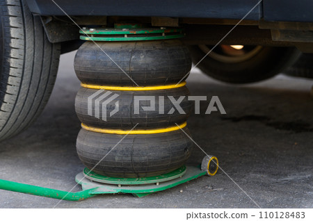 A pneumatic jack supports the vehicle while changing tires. 110128483