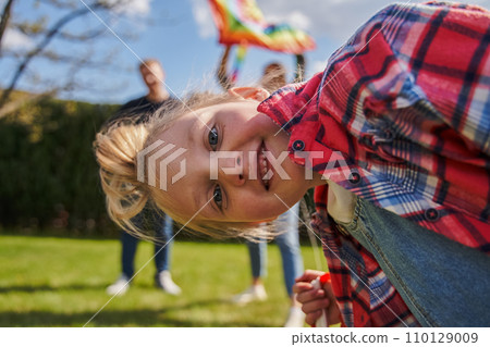 Overjoyed little kid looking camera while playing with her parents outdoors 110129009