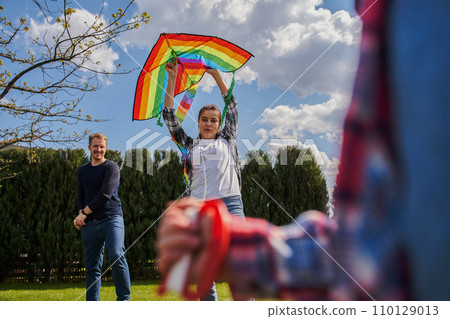 Overjoyed woman holding kite while playing with her kid and husband 110129013