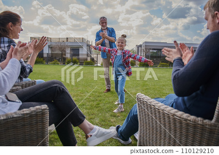 Happy family of three generations clapping hands while little girl standing with spread arms Happy family of three generations clapping hands while little girl standing with spread arms 110129210