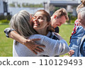 Happy woman embracing her mother while standing at the green grass lawn 110129493