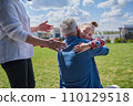 Cute little girl embracing her grandfather while standing at the green grass lawn 110129518