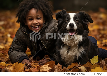 Energetic black boy having fun with his dog outdoors in the park in autumn 110129593