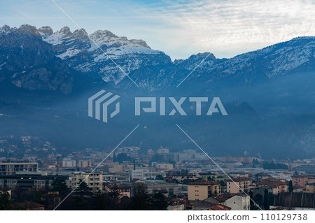 Beautiful landscape of the layered misty hazy Italian Alps mountain range during evening. Lombardy, Italy Beautiful landscape of the layered misty hazy Italian Alps mountain range during evening. Lombardy, Italy 110129738