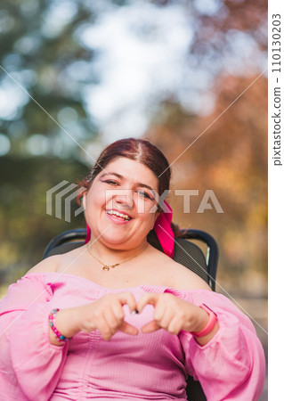 InspireInclusion heart shape, love valentine gesture. Young woman with cerebral palsy disability.  110130203