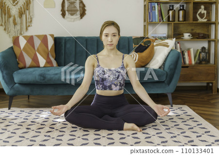 Young brown-haired woman doing yoga in the living room Young brown-haired woman doing yoga in the living room 110133401