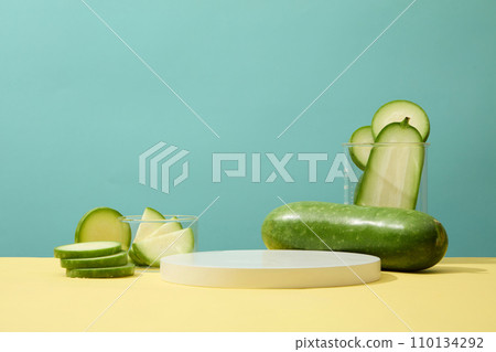 Round slices of winter melon decorated on yellow surface with a round podium. Blank space on the podium for cosmetic promotion of Winter melon (Benincasa hispida) extract 110134292