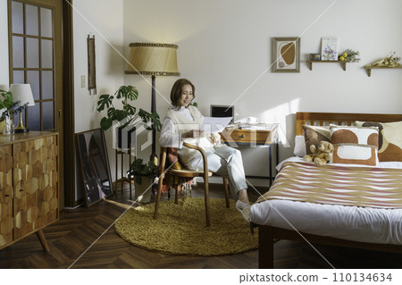 A young brown-haired woman works while sitting at her desk at home A young brown-haired woman works while sitting at her desk at home 110134634