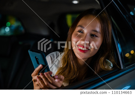 Happy beautiful woman texting smartphone sitting car back seat in urban, Asian businesswoman working late commuting from office in Taxi backseat with mobile phone in city at night after late work Happy beautiful woman texting smartphone sitting car back seat in urban, Asian businesswoman working late commuting from office in Taxi backseat with mobile phone in city at night after late work 110134663