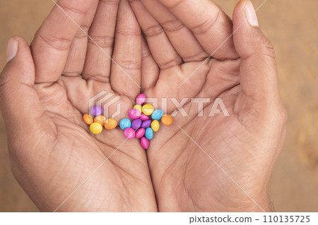colorful candy in the hand of a child on a brown background colorful candy in the hand of a child on a brown background 110135725