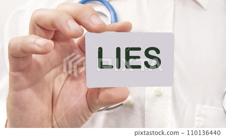 Lies word on the card in a man's hand on the background of a white shirt 110136440