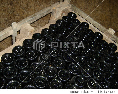 wine dusty bottles upside down in a box for storing and brewing wine. Wine cellar equipment. The process of making expensive French wine. Dust on a Dark Glass Bottle wine dusty bottles upside down in a box for storing and brewing wine. Wine cellar equipment. The process of making expensive French wine. Dust on a Dark Glass Bottle 110137488