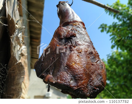 Homemade ham. Farm product of Serbian producers. Dried salted smoky pork hind leg. Meat delicacy. Meat suspended in the air to dry. Protein diet. Traditional cooking 110137782
