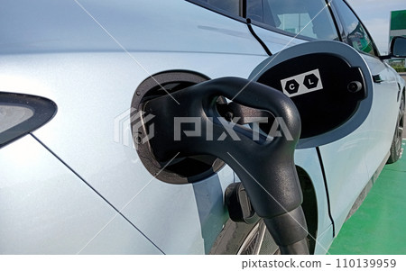 Electric car charging at plug in charge station Electric car charging at plug in charge station 110139959
