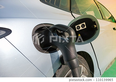 Electric car charging at plug in charge station Electric car charging at plug in charge station 110139965