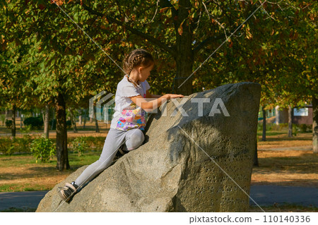 Children's emotions. Offended child sitting on a stone in a city park 110140336