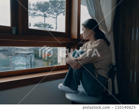 Woman fall depression sitting by the window and looking at nature, rainy weather and discouragement, home life style, loneliness. Woman fall depression sitting by the window and looking at nature, rainy weather and discouragement, home life style, loneliness. 110140825