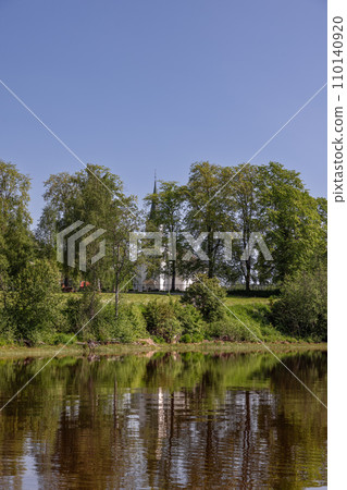 Historic Kvam Church on Snasavatnet's shore, framed by tree silhouettes 110140920