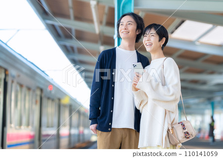 一對年輕夫婦在車站看智慧型手機。攝影由京王電鐵株式會社提供。 110141059