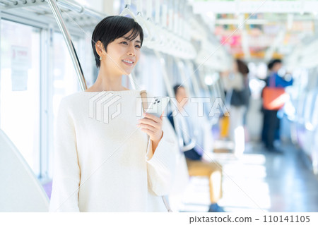 Young woman looking at a smartphone by train "Keio Electric Railway Co., Ltd." 110141105