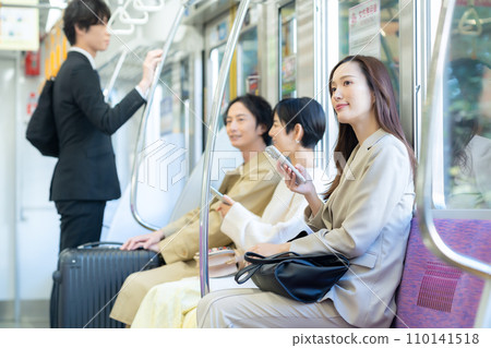 A young businesswoman commuting by train while looking at her smartphone. Photography cooperation: Keio Electric Railway Co., Ltd. 110141518