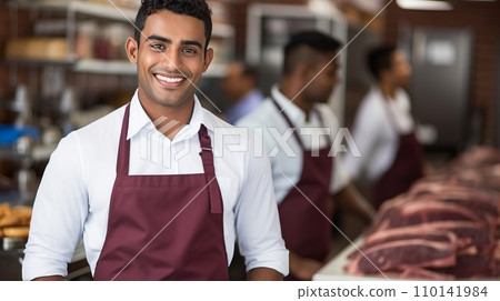 Smiling Young Butcher with Expertise, Assisting Customers at the Well-Stocked Meat Counter Smiling Young Butcher with Expertise, Assisting Customers at the Well-Stocked Meat Counter 110141984