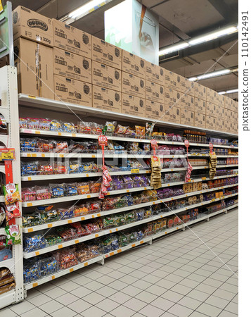 MELAKA, MALAYSIA -APRIL 19, 2022: Selective focused on packed miscellaneous brand junk foods and snacks on the rack and display for sale in the supermarket. Each has its own price tag.  110142491