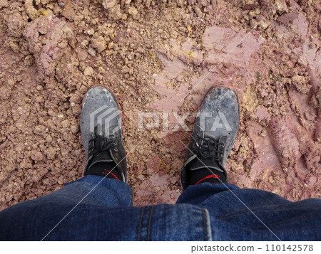 Top or side view of construction worker standing on construction site while wearing safety shoes. The shoes are dirty and dusty. Top or side view of construction worker standing on construction site while wearing safety shoes. The shoes are dirty and dusty. 110142578