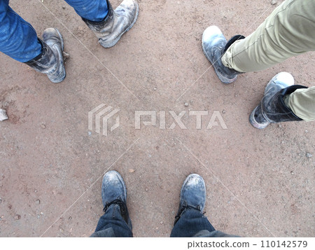 Top or side view of construction worker standing on construction site while wearing safety shoes. The shoes are dirty and dusty. 110142579