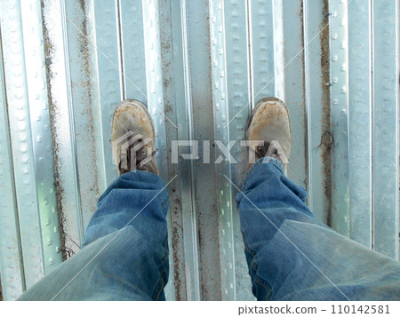 Top or side view of construction worker standing on construction site while wearing safety shoes. The shoes are dirty and dusty. Top or side view of construction worker standing on construction site while wearing safety shoes. The shoes are dirty and dusty. 110142581