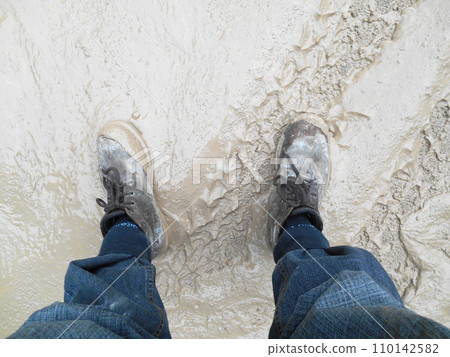 Top or side view of construction worker standing on construction site while wearing safety shoes. The shoes are dirty and dusty. 110142582