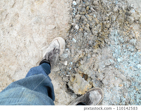 Top or side view of construction worker standing on construction site while wearing safety shoes. The shoes are dirty and dusty. Top or side view of construction worker standing on construction site while wearing safety shoes. The shoes are dirty and dusty. 110142583