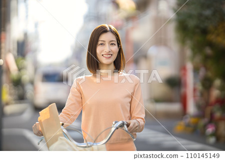 Middle-aged woman going shopping by bicycle Middle-aged woman going shopping by bicycle 110145149