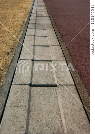 Rainwater gutter that separates the ground and lawn in a winter park Rainwater gutter that separates the ground and lawn in a winter park 110145512