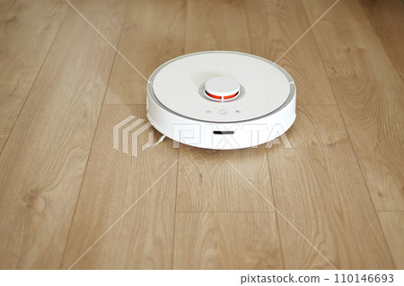 Wireless autonomous smart robotic vacuum cleaner is vacuuming floor with modern tiles at living room. Self-propelled cleaning robot. Floor cleaning system. Household remote control appliances. Wireless autonomous smart robotic vacuum cleaner is vacuuming floor with modern tiles at living room. Self-propelled cleaning robot. Floor cleaning system. Household remote control appliances. 110146693