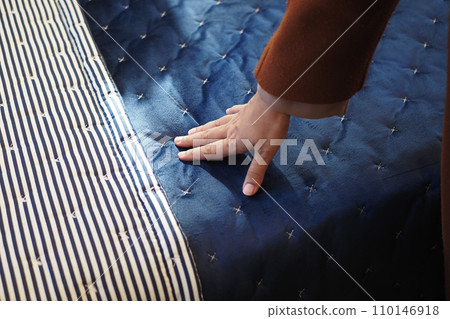 Hand touching and pressing orthopedic mattress on bed. 110146918