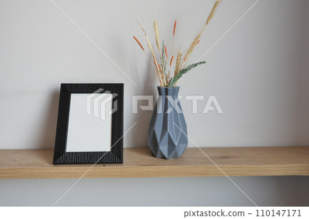 empty photo frame on table against white wall  110147171