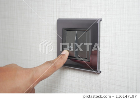 A finger turning on lighting switch . A finger turning on lighting switch . 110147197