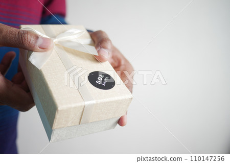 hand putting a thank you sticker on a gift box  110147256