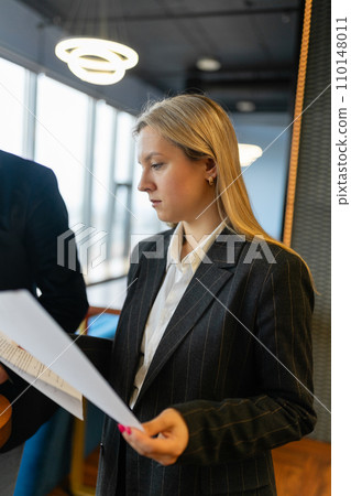 Woman worker with blond hair examines information in report 110148011