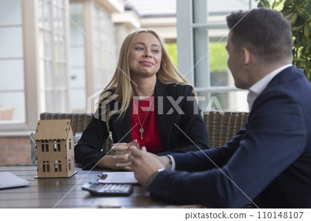 Blonde estate agent listens to potential client in terrace Blonde estate agent listens to potential client in terrace 110148107