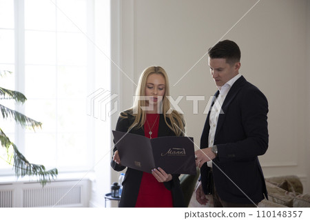Woman holds folder and talks to manager in light room 110148357